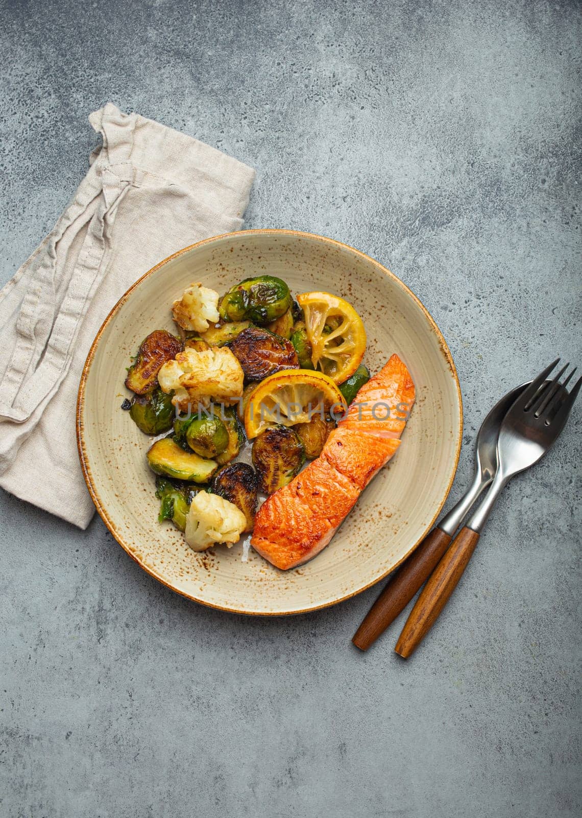 Delicious salmon fillet with grilled Brussels sprouts on plate, rustic concrete background top view. Healthy dinner with grilled fish and vegetables, balanced nutrition by its_al_dente