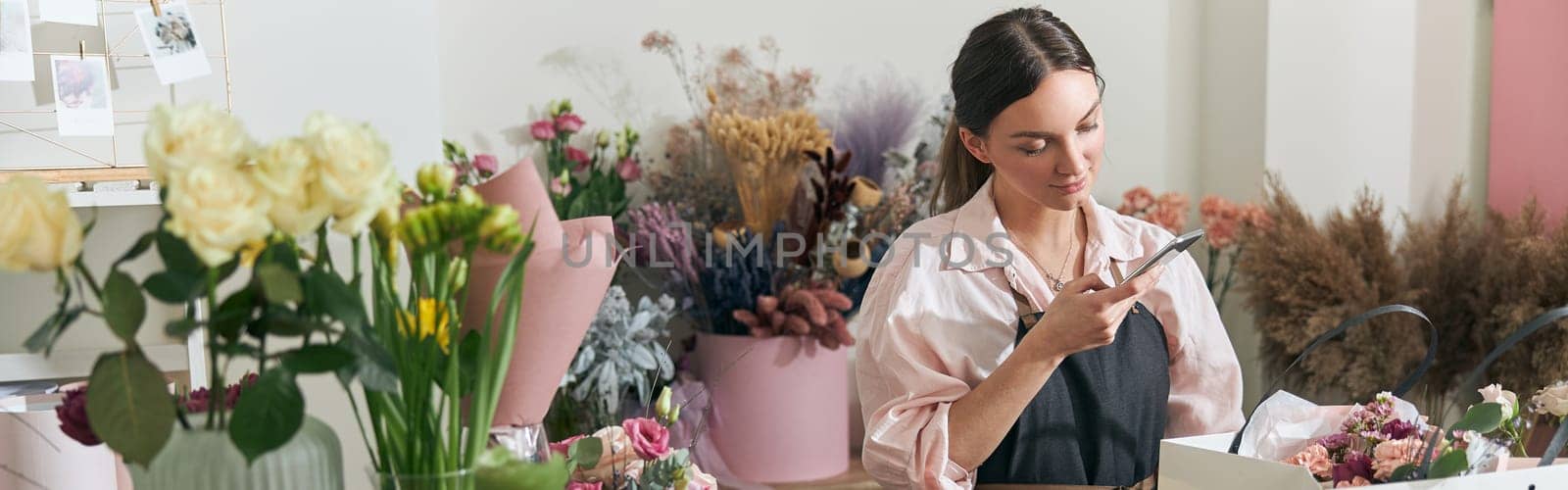 Professional florist young woman is doing bouquets at flower shop