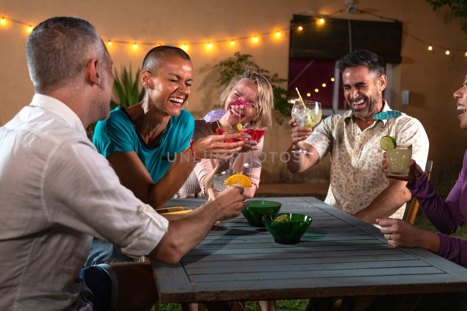 Group of friends enjoying some cocktails after dinner outdoors in the garden. Having fun together and laughing, Lifestyle concept.