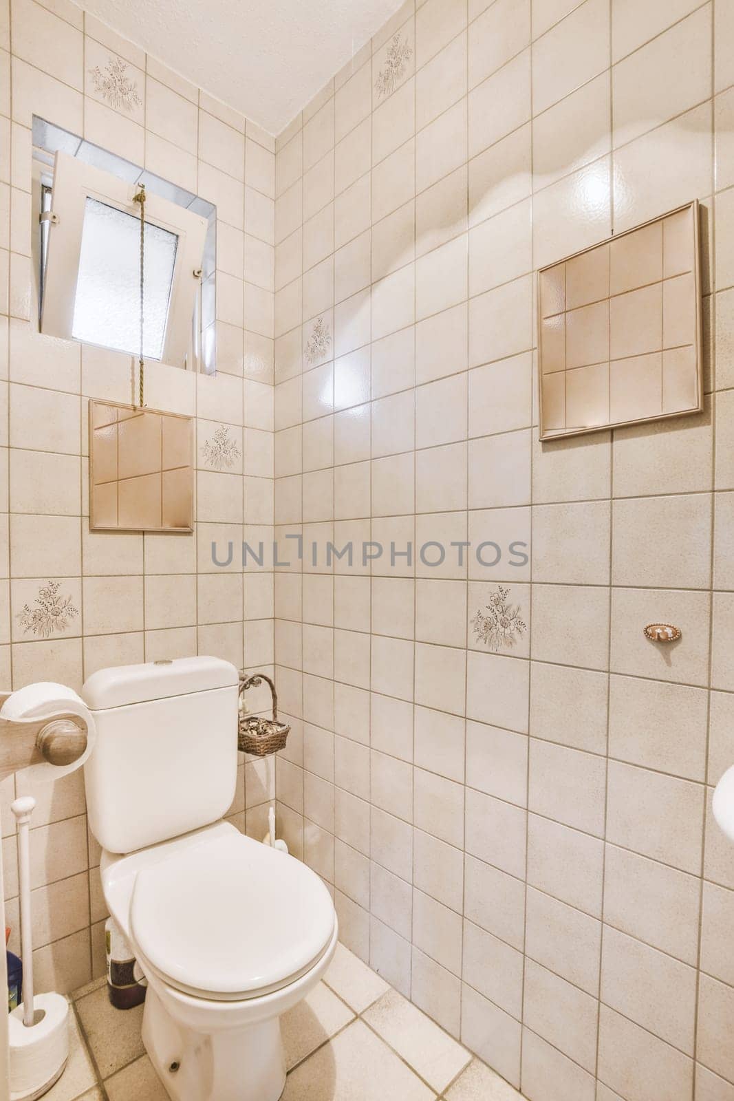 a white toilet in a bathroom with tile on the floor and wall behind it, there is a mirror above the toilet
