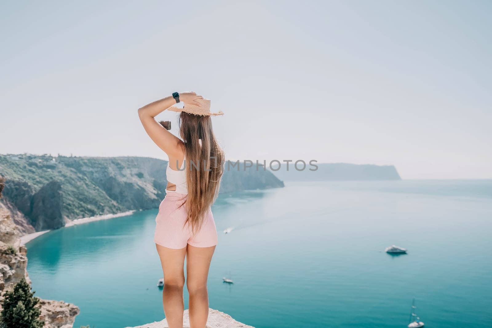 Woman sea laptop. Business woman in yellow hat freelancer with laptop working over blue sea beach. Girl relieves stress from work. Freelance, digital nomad, travel and holidays concept by panophotograph