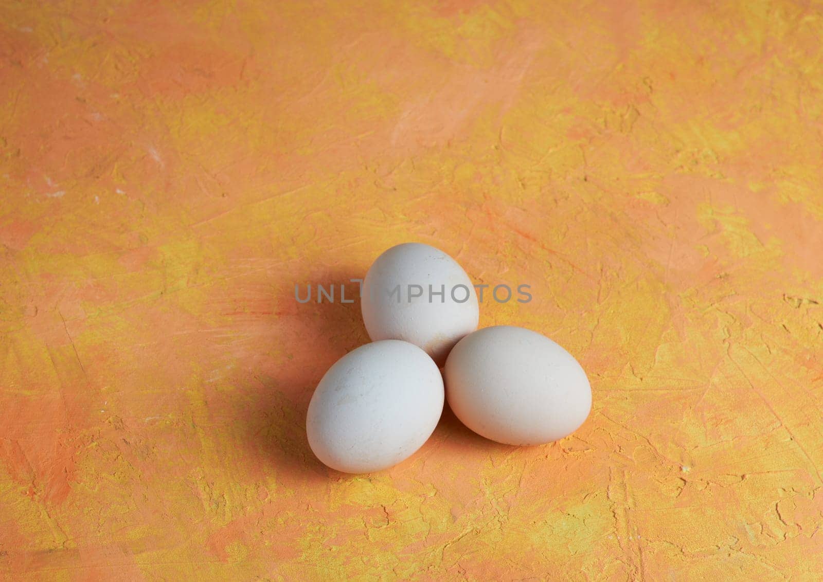 Three Easter white eggs on a yellow background by Севостьянов