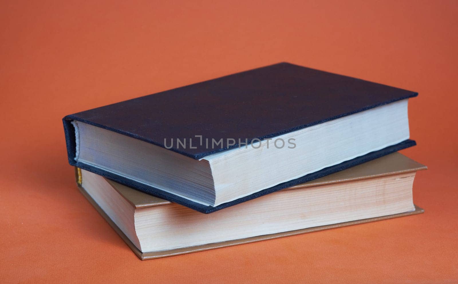 Two hardcover books on top of each other on a brown background. White and black book.