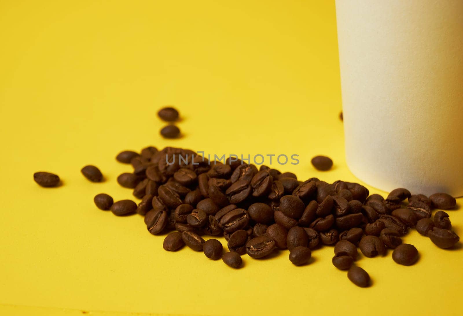 coffee beans next to a paper cup on a yellow background by Севостьянов