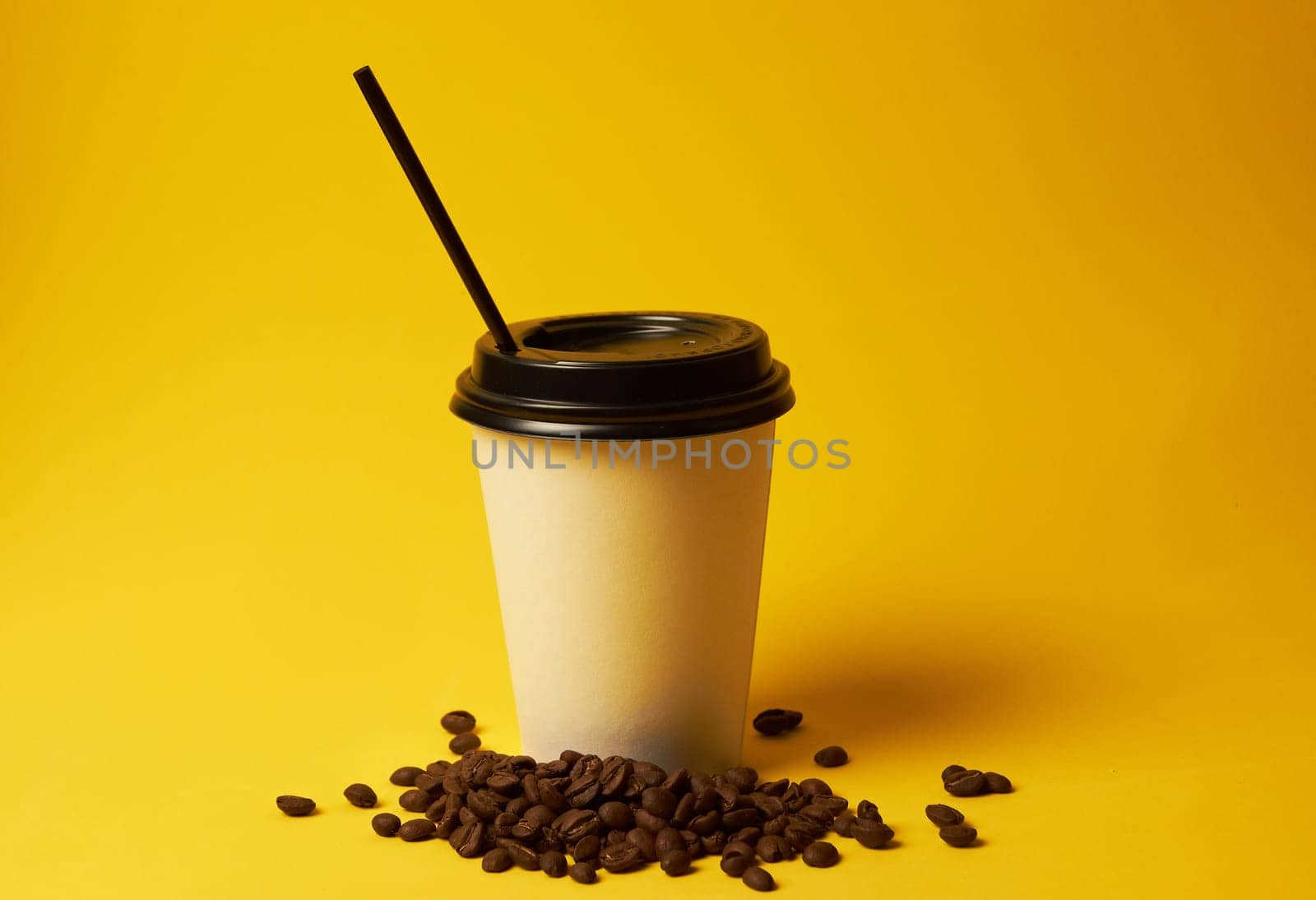 Paper coffee container with a black lid and coffee beans on a yellow background white coffee paper cup with a black lid takeaway coffee