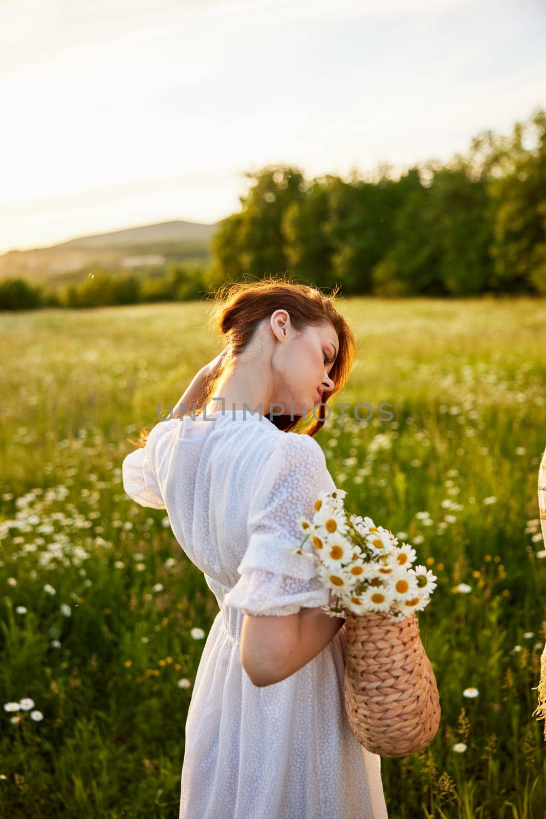 close portrait of a woman turned away from the camera in a light dress and a wicker basket in her hands with chamomile flowers in nature by Vichizh