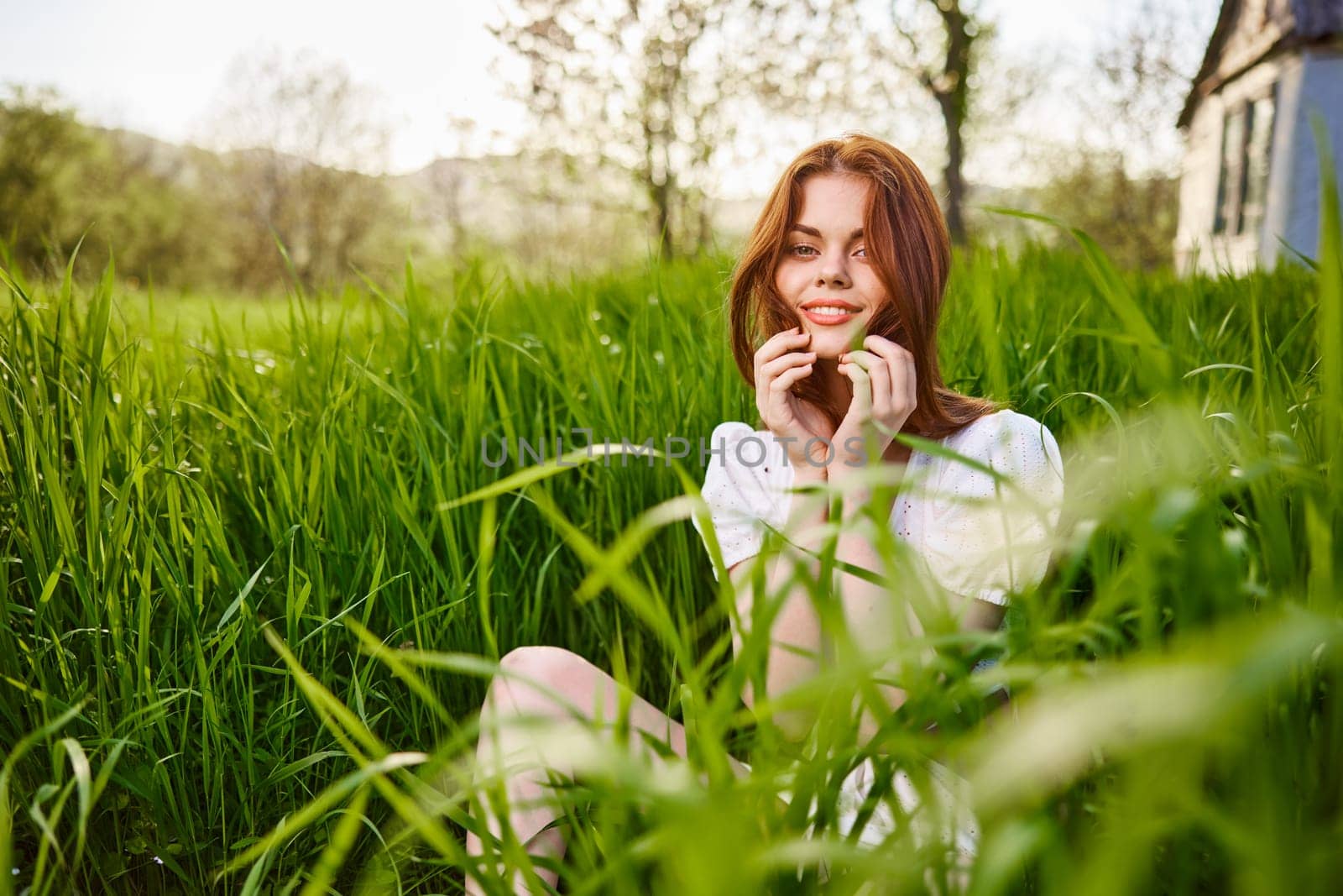 happy smiling redhead woman resting sitting in tall grass by Vichizh