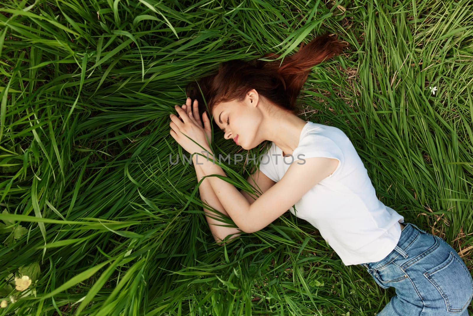 serene, woman lies in green tall grass in casual clothes by Vichizh