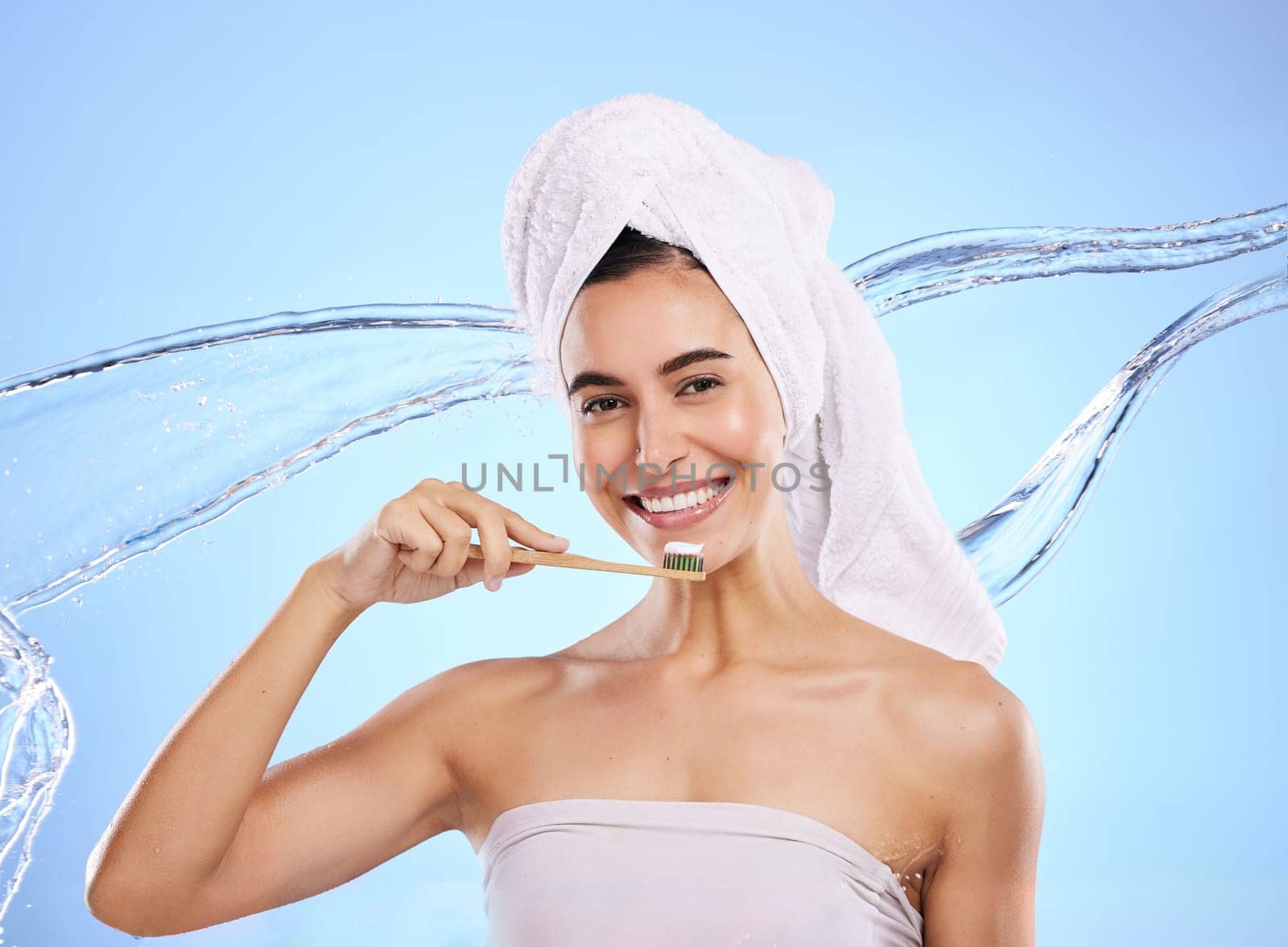 Woman, water splash and toothbrush for teeth, dental care or skincare hygiene against blue studio background. Portrait of happy female smile in tooth whitening, oral or mouth treatment for healthcare by YuriArcurs