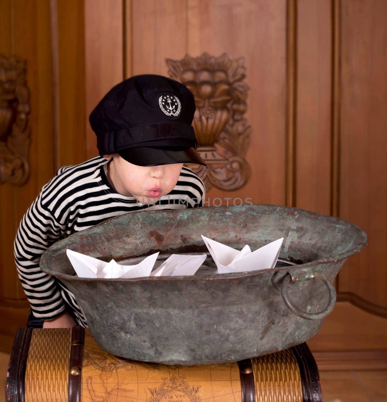 The boy dreams of becoming a sailor. A child launches paper boats in a bowl of water at home by aprilphoto