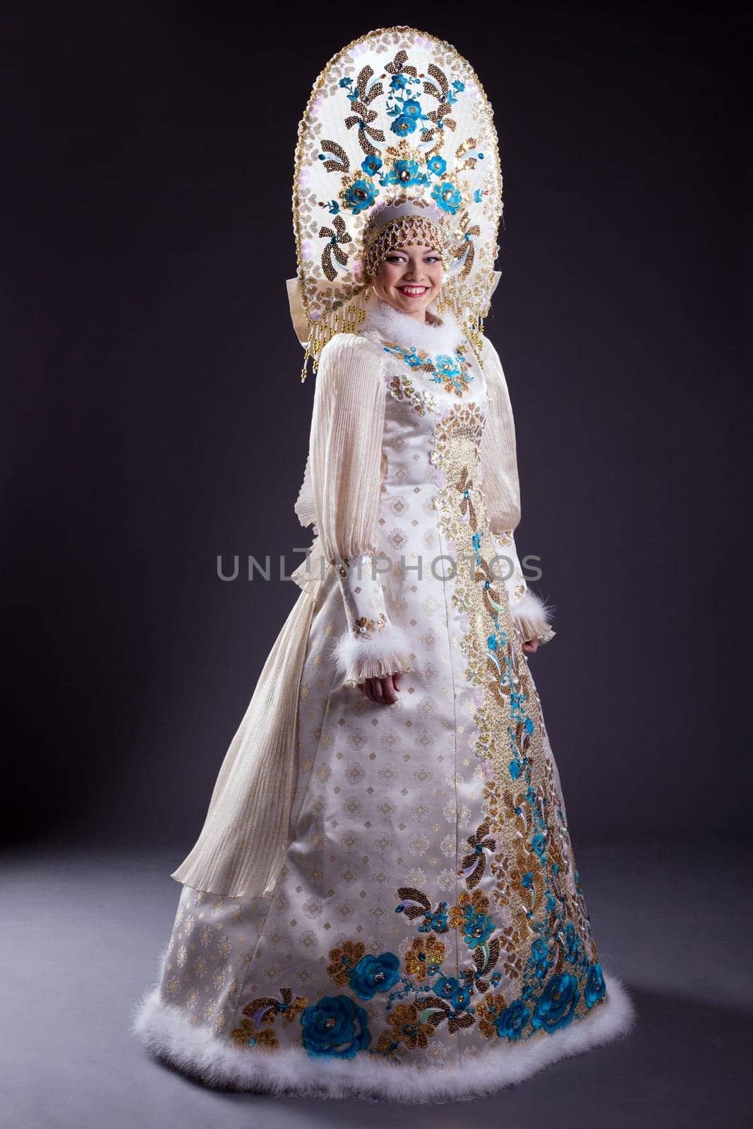 Smiling woman in Russian costume and kokoshnik on gray background