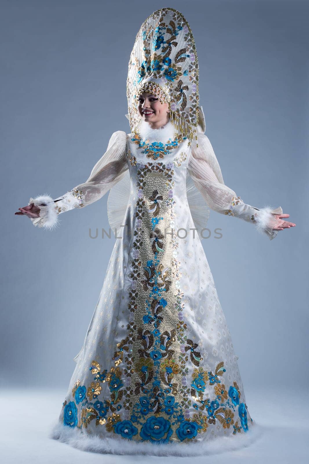 Cheerful woman in luxurious traditional costume, on blue background
