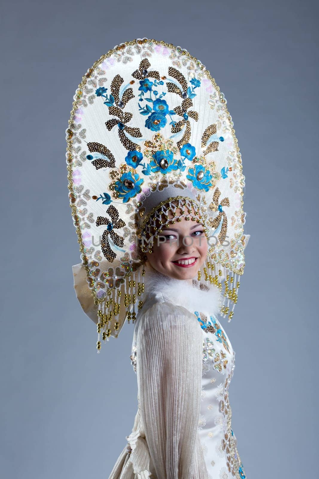 Portrait of smiling young woman in kokoshnik, on blue background