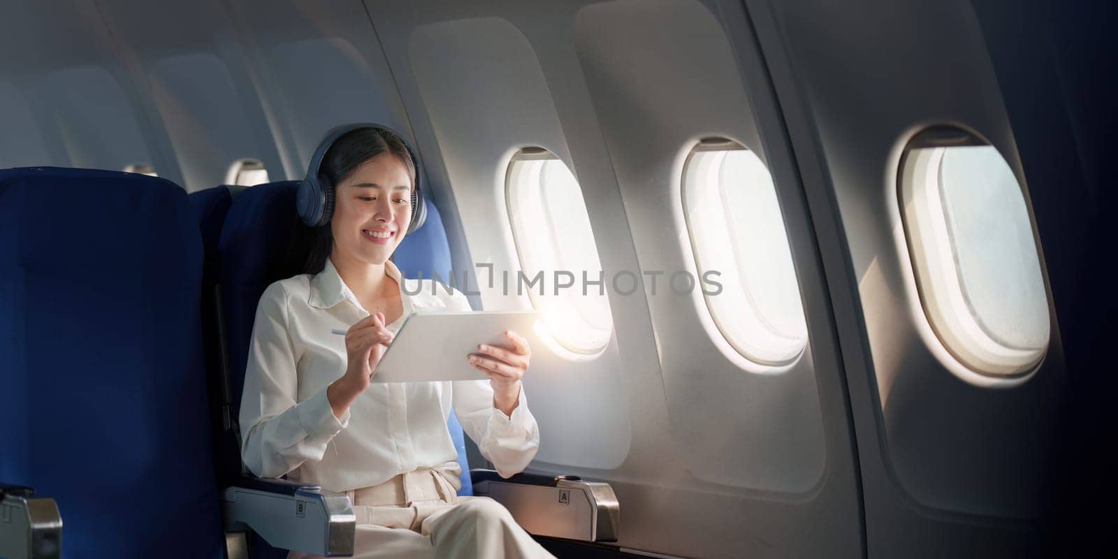 Beautiful Asian businesswoman working with digital tablet in aeroplane. working, travel, business concept.