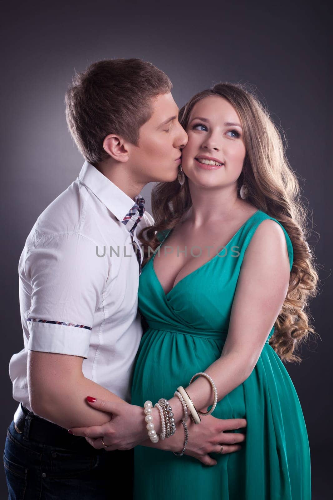 Image of man kissing cheerful pregnant woman by rivertime