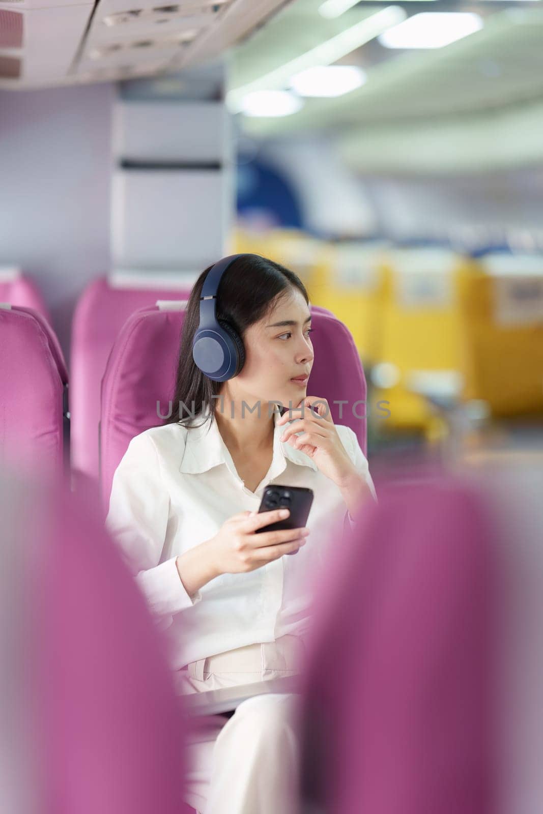 Beautiful Asian business woman listen music by mobile phone during flight in aeroplane. working, travel, business concept by itchaznong