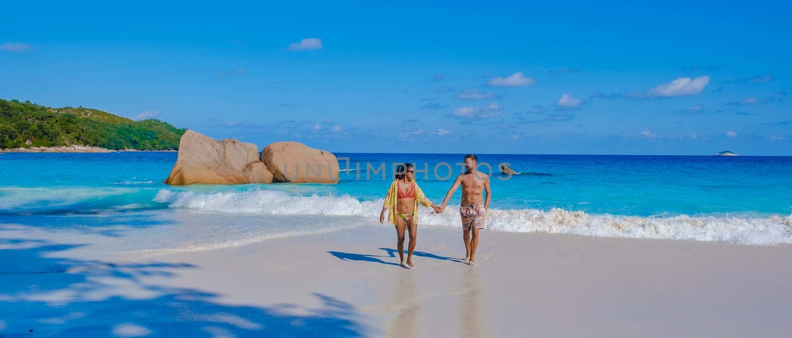 Praslin Seychelles tropical island with white beaches and palm trees, a couple of men and women mid age on vacation at Seychelles visiting the tropical beach of Anse Lazio Praslin Seychelles.