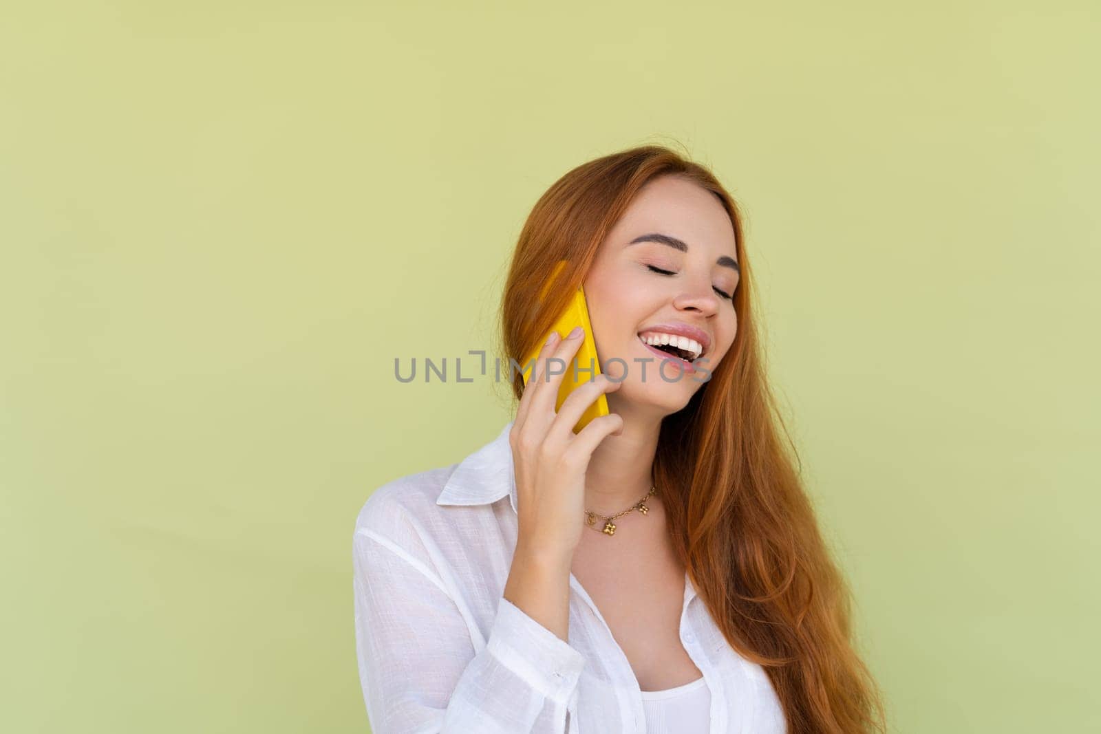 Beautiful red hair woman in casual shirt on green background talk on mobile phone smile and laugh