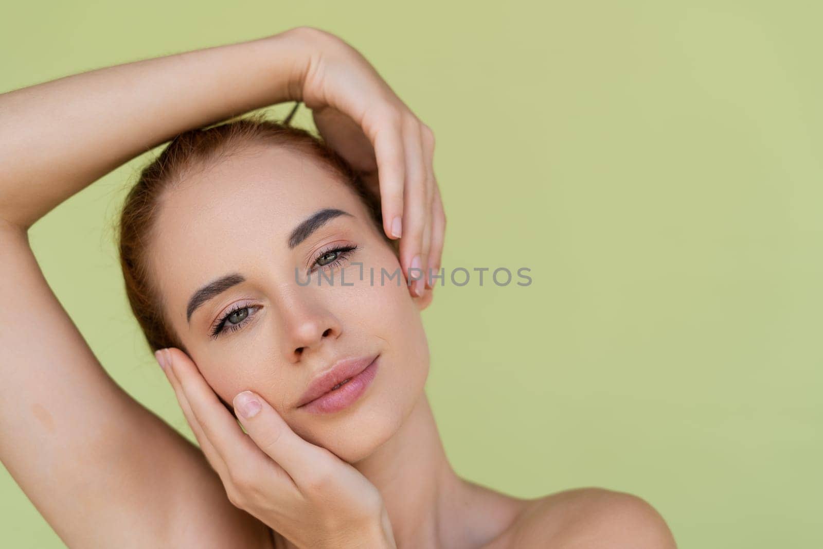 Beauty portrait of young topless red hair woman with bare shoulders on green background with perfect skin and natural makeup