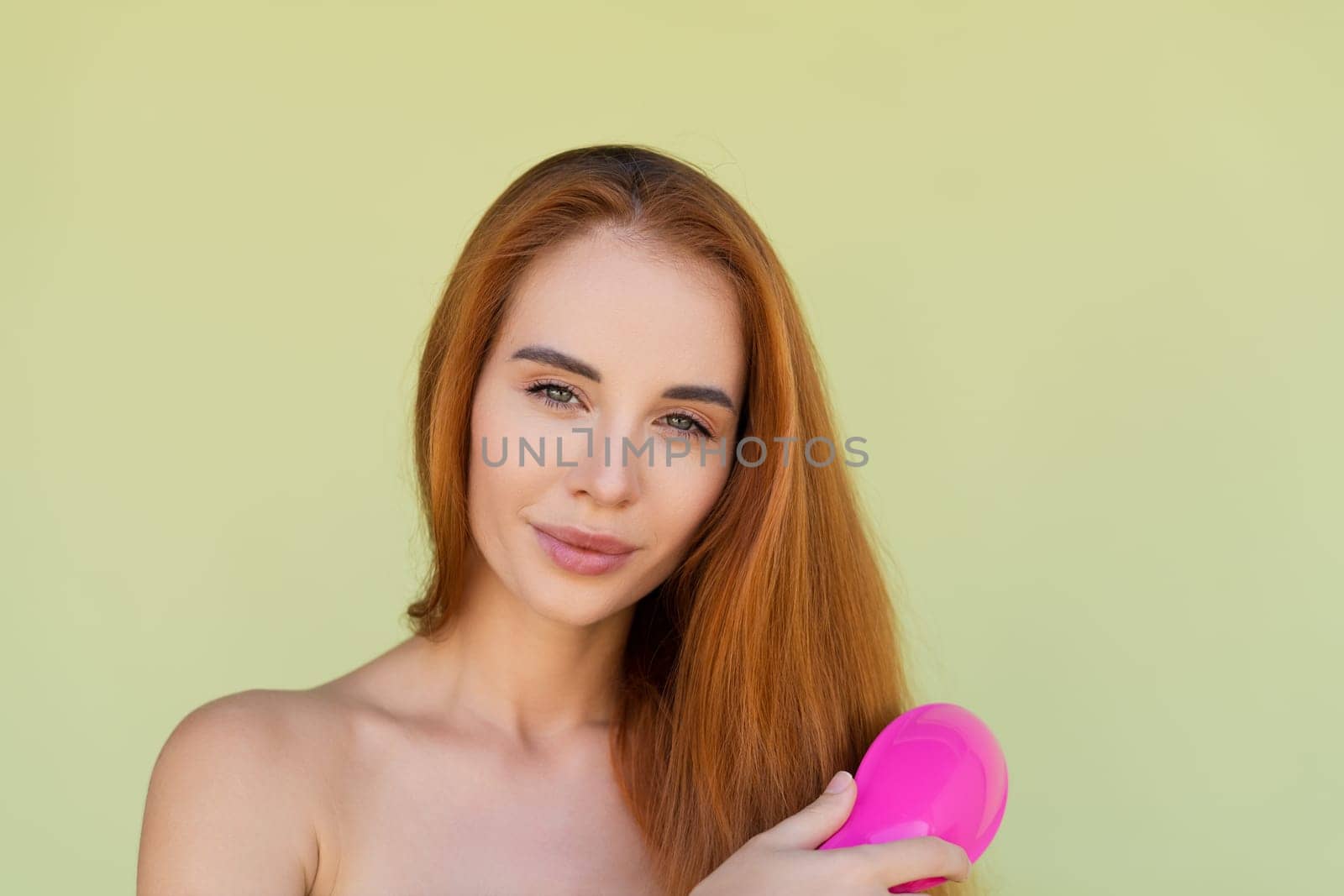 Beauty portrait of young topless red hair woman with bare shoulders on green background brush long strong shiny hair by kroshka_nastya