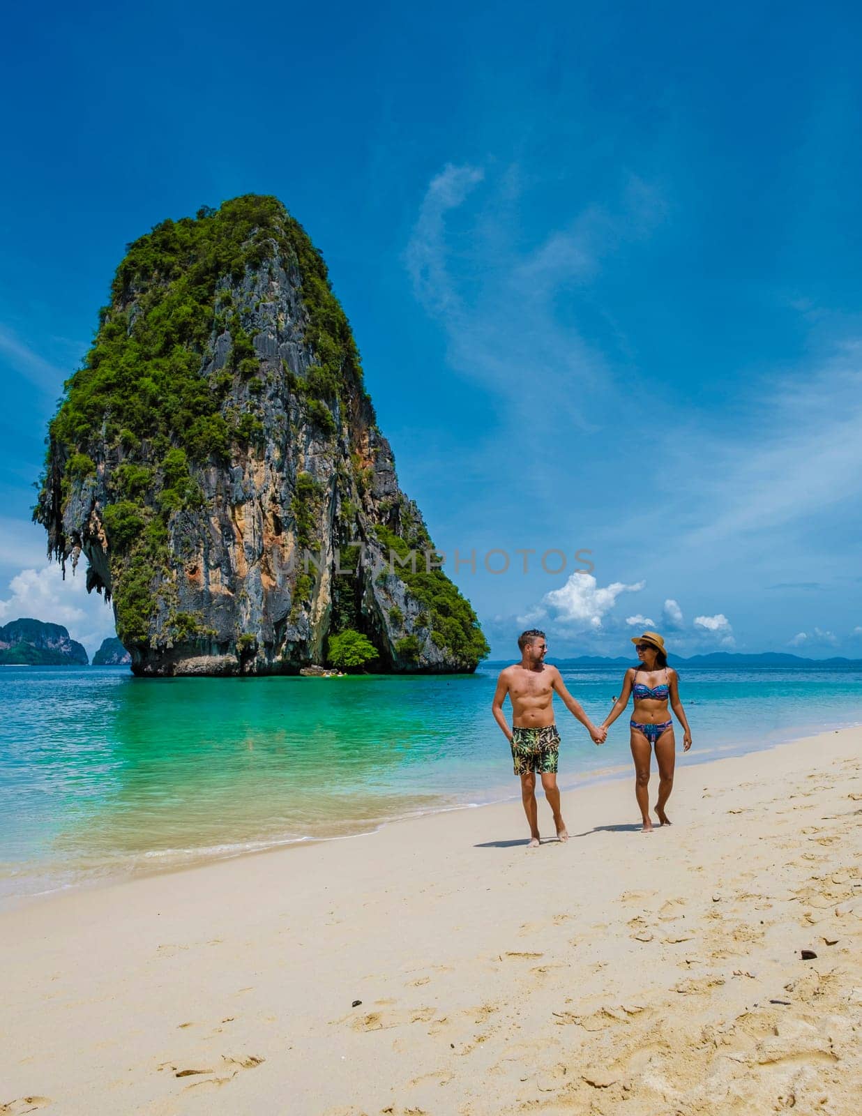 Railay beach Krabi Thailand, tropical beach of Railay Krabi, couple men and woman on the beach, Panoramic view of idyllic Railay Beach in Thailand with a traditional long boat by fokkebok