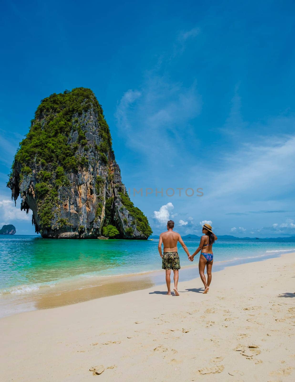 Railay Beach Krabi Thailand, the tropical beach of Railay Krabi, a couple of men and woman on the beach, Panoramic view of idyllic Railay Beach in Thailand with a traditional long boat.