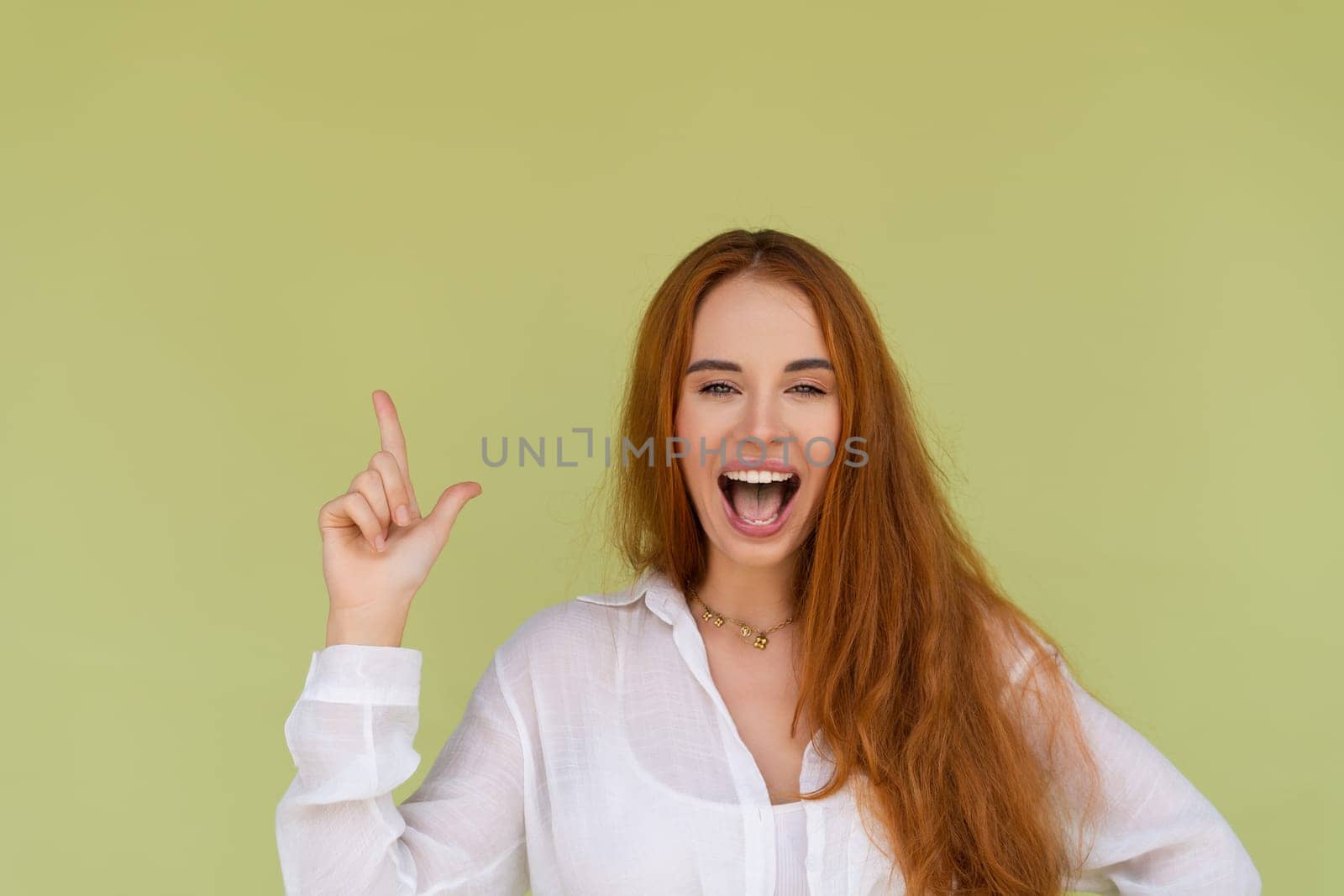 Beautiful red hair woman in casual shirt on green background happy look to camera surprised with mouth open point finger up by kroshka_nastya