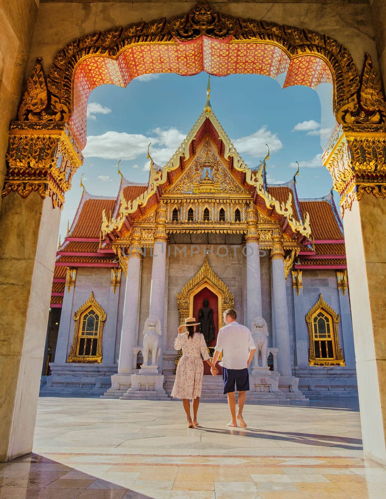 Wat Benchamabophit temple in Bangkok Thailand, The Marble temple in Bangkok. Asian woman with a hat and European men visiting a temple, a couple on a city trip in Bangkok