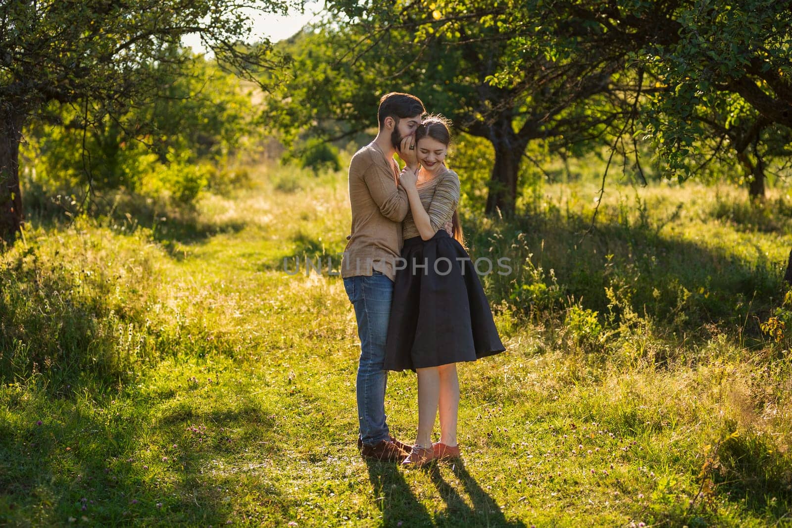 man tells in his ear the secret of his girlfriend walking in the park