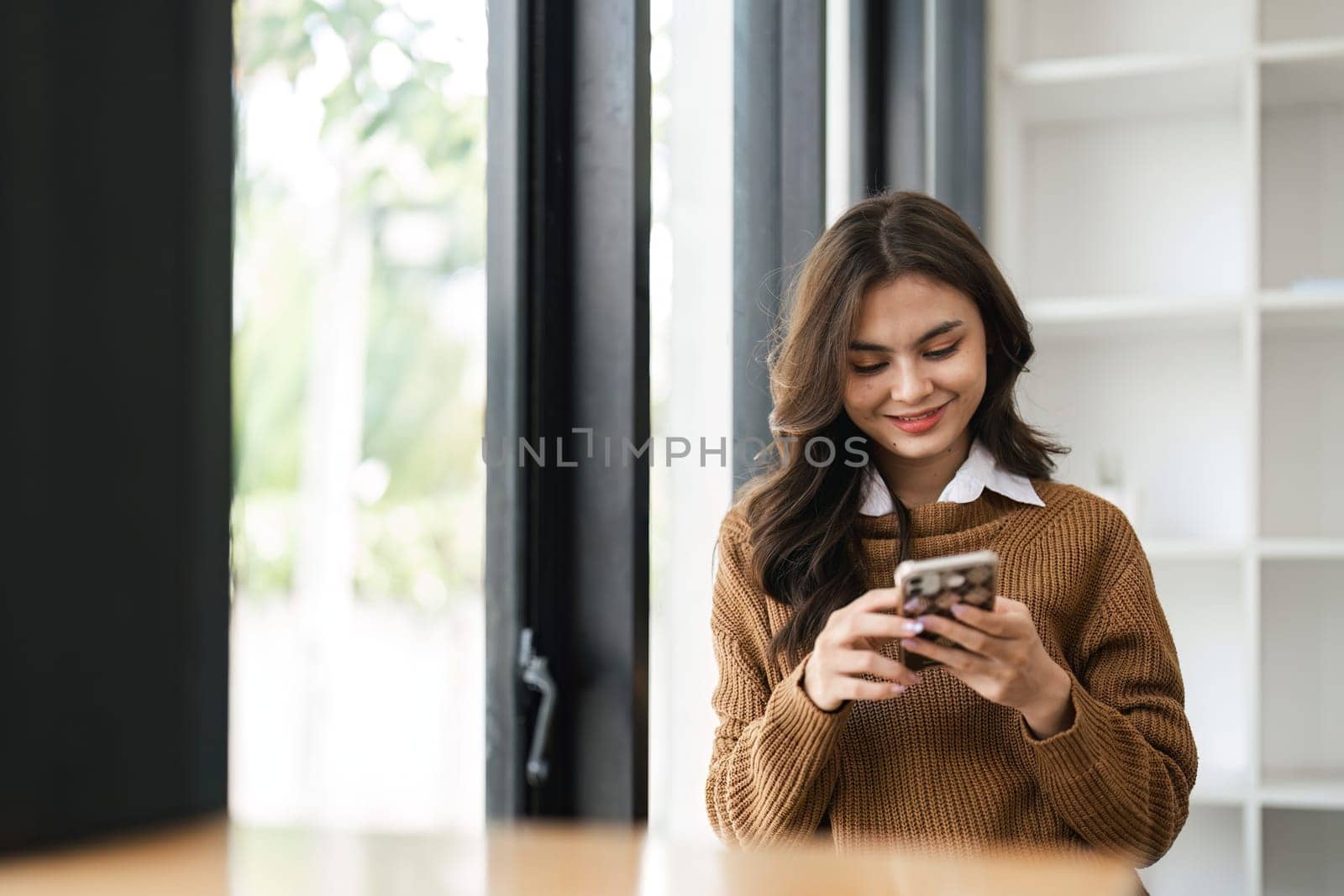 A beautiful young woman holding and using mobile phone by nateemee