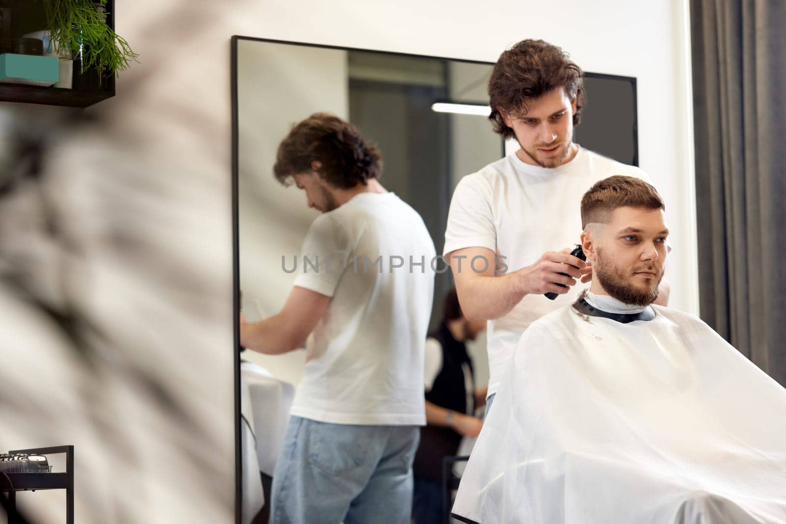 man visiting professional hairstylist in barber shop by erstudio