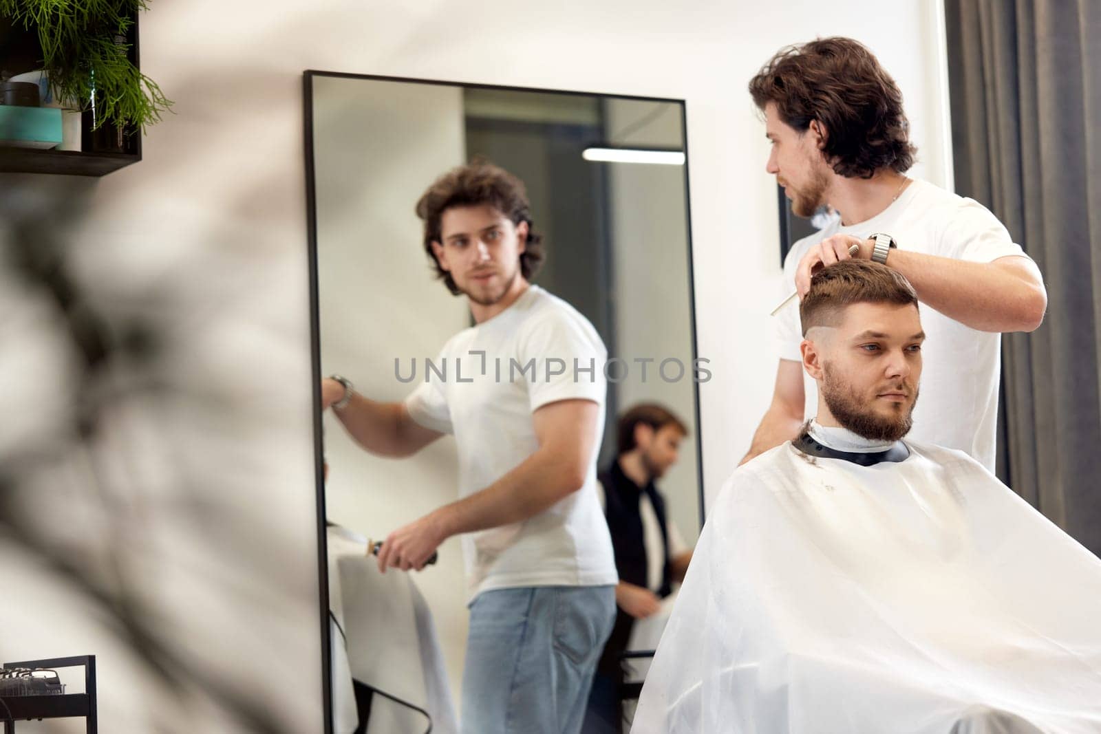 handsome young man visiting professional hairstylist in barber shop