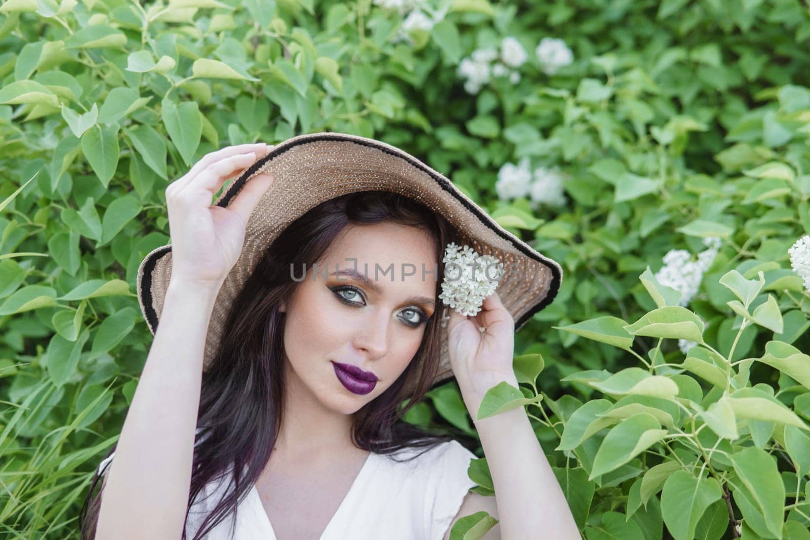 A fashionable girl with dark hair, a spring portrait in lilac tones in summer. Bright professional makeup