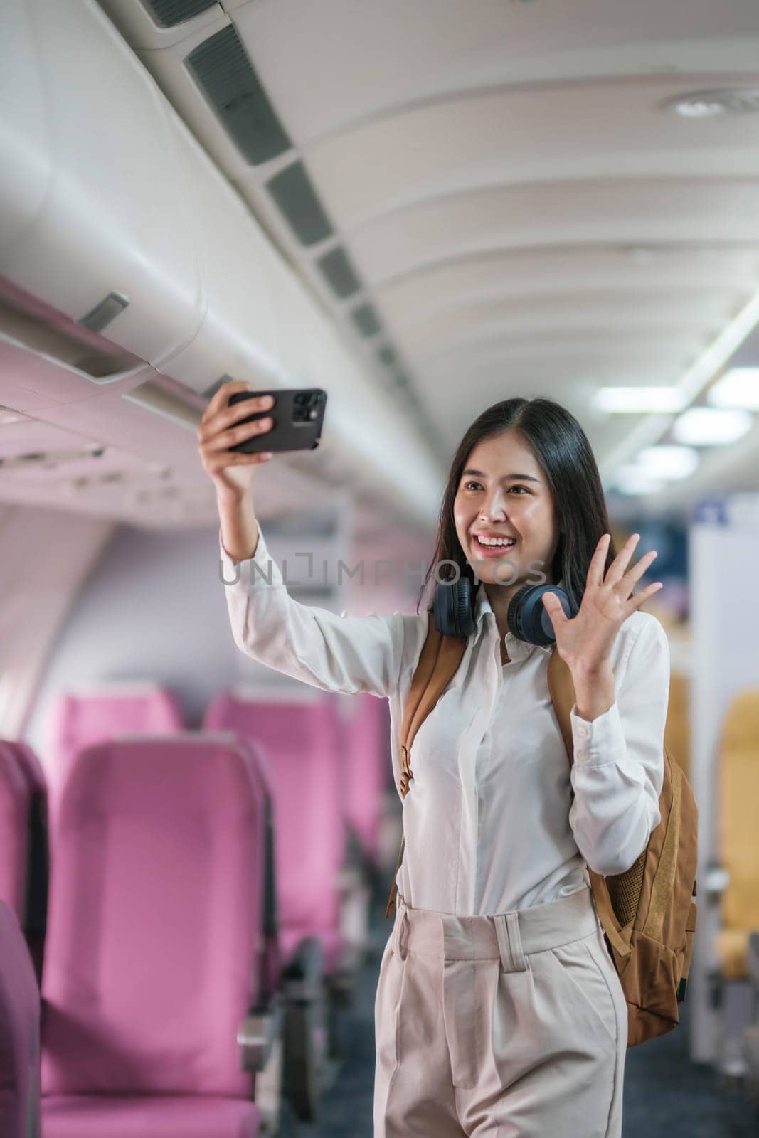 Portrait of an Asian woman taking a selfie or capturing memories while waiting for an economy class flight. Travel concept, vacations, tourism by wichayada