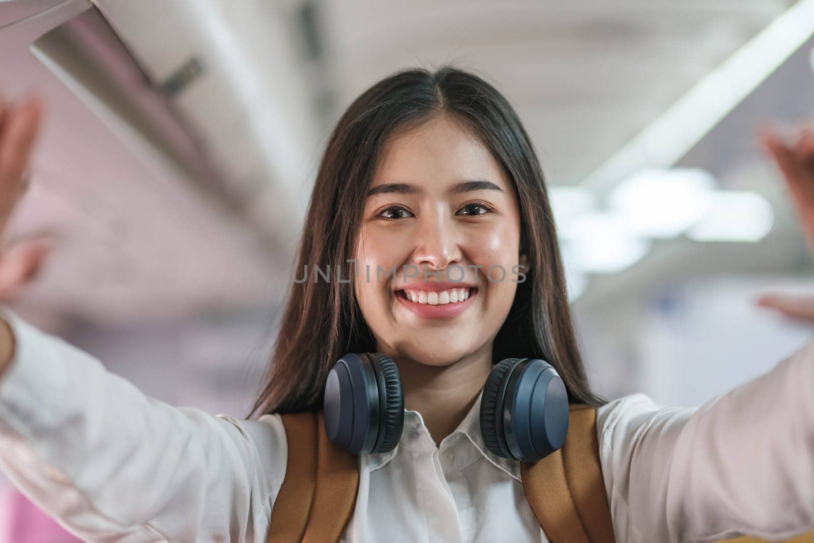 Portrait of an Asian woman taking a selfie or capturing memories while waiting for an economy class flight. Travel concept, vacations, tourism..