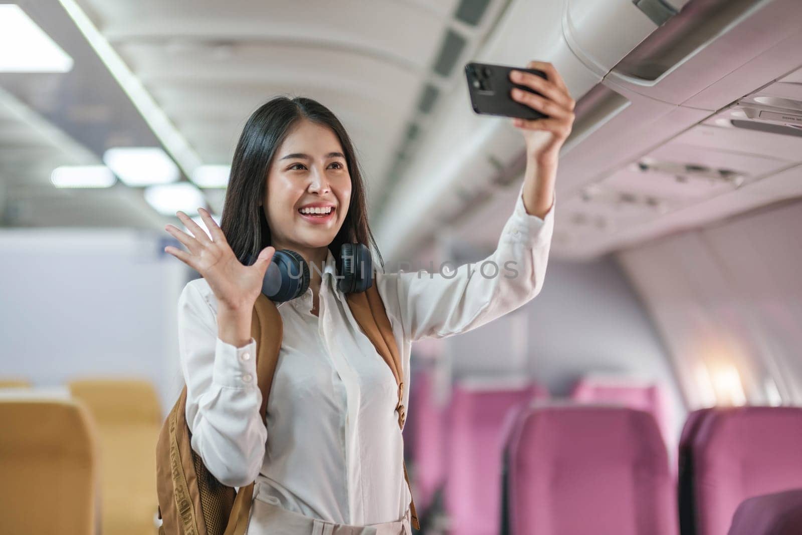 Portrait of an Asian woman taking a selfie or capturing memories while waiting for an economy class flight. Travel concept, vacations, tourism..