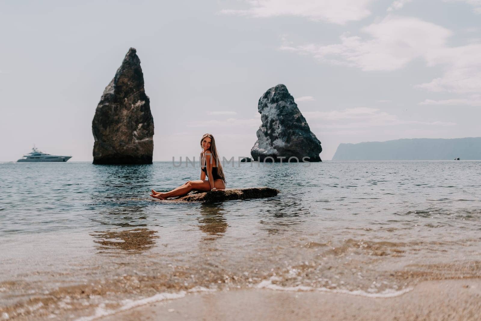 Woman summer travel sea. Happy tourist enjoy taking picture outdoors for memories. Woman traveler posing on the beach at sea surrounded by volcanic mountains, sharing travel adventure journey by panophotograph