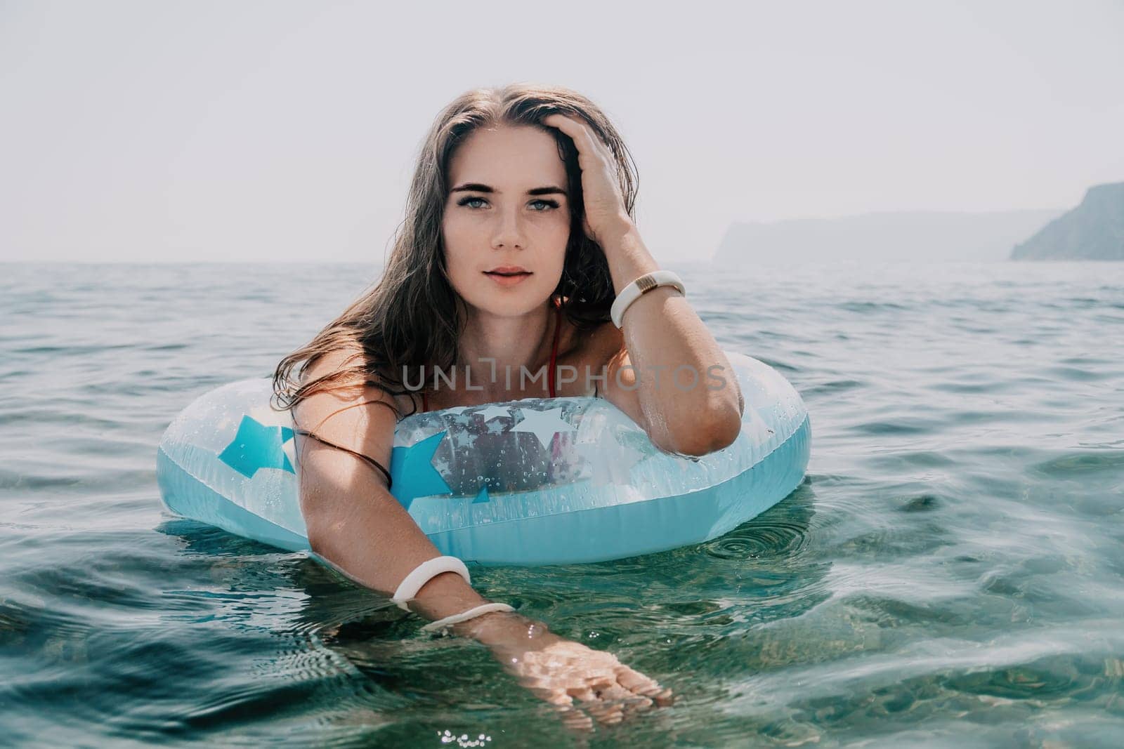 Woman summer sea. Happy woman swimming with inflatable donut on the beach in summer sunny day, surrounded by volcanic mountains. Summer vacation concept. by panophotograph