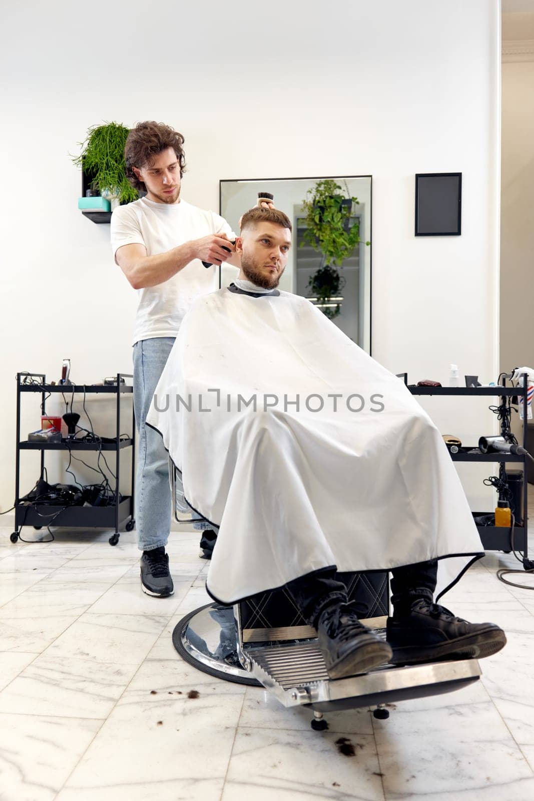 Barber trim hair with clipper on handsome bearded man by erstudio