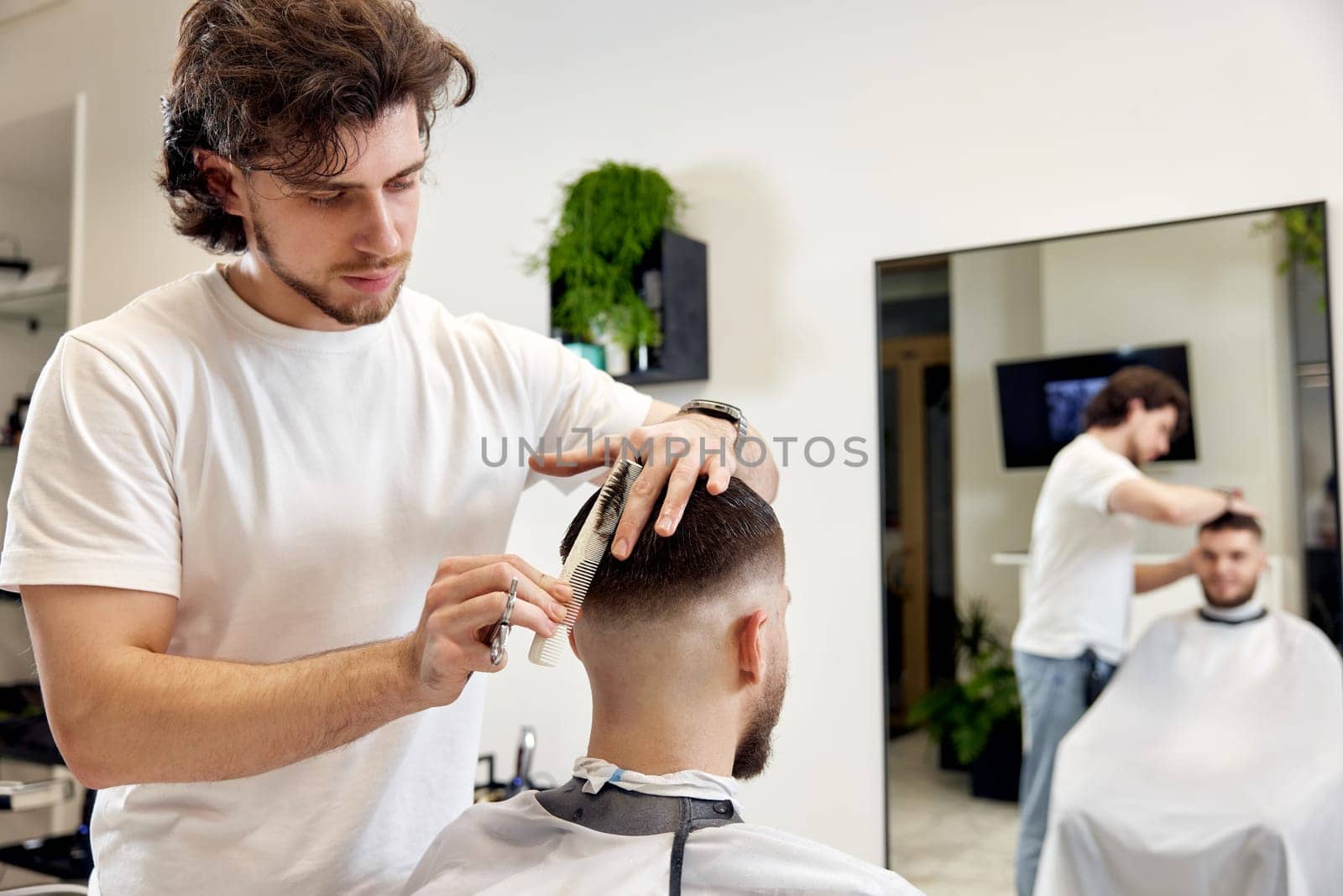 hairdresser does haircut for man using comb and grooming scissors by erstudio