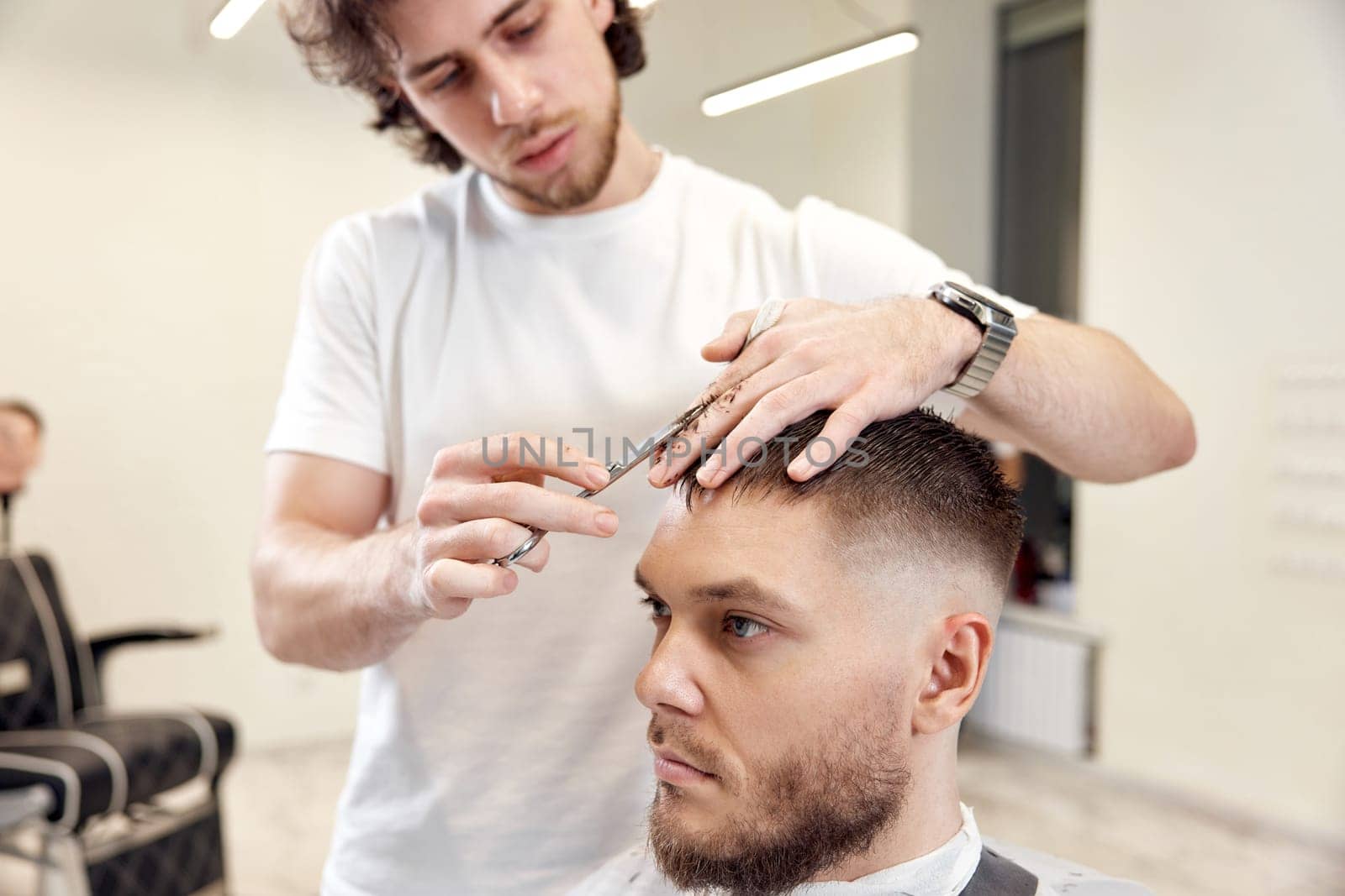 hairdresser does haircut for man using comb and grooming scissors by erstudio