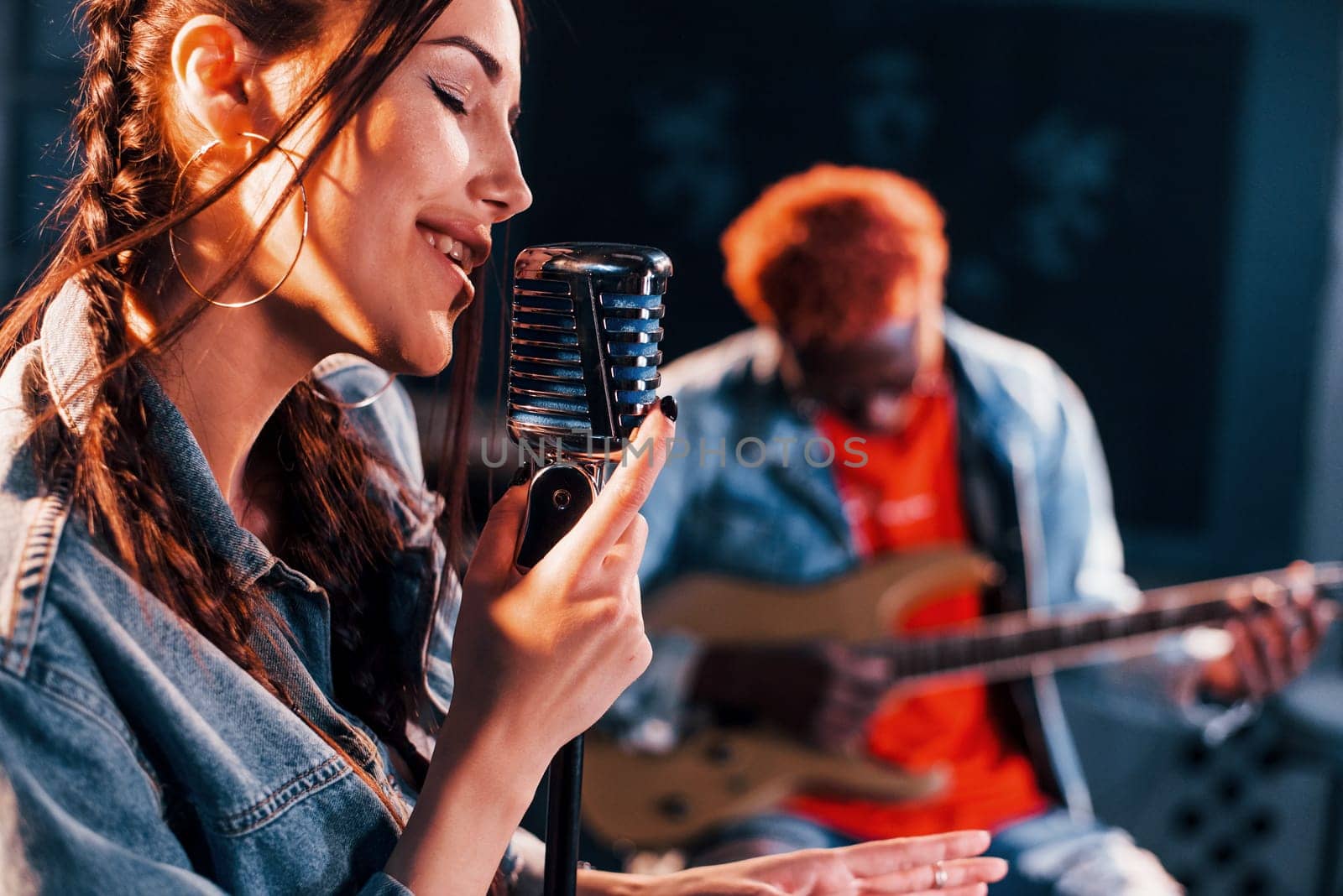 Guy plays guitar, girl sings. African american man with white girl rehearsing in the studio together by Standret