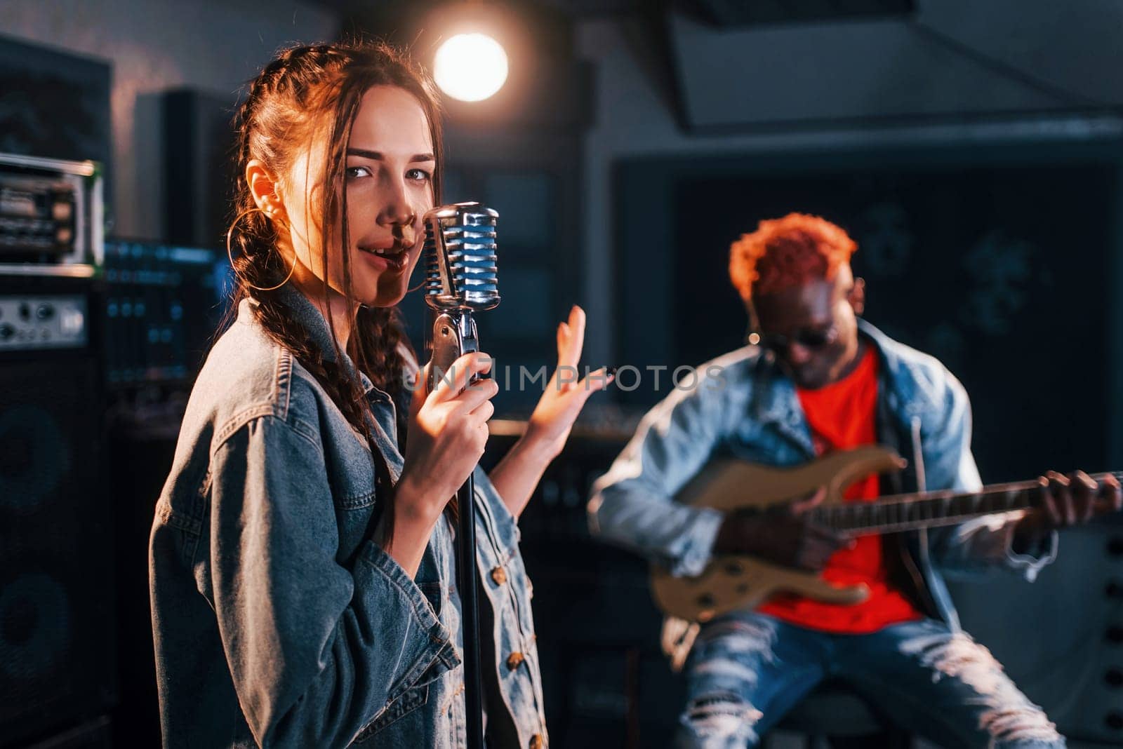 Guy plays guitar, girl sings. African american man with white girl rehearsing in the studio together by Standret