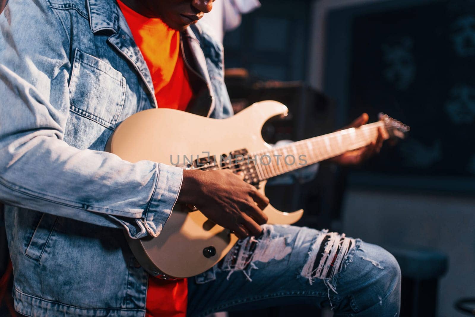 Plays guitar. Young african american performer rehearsing in a recording studio by Standret