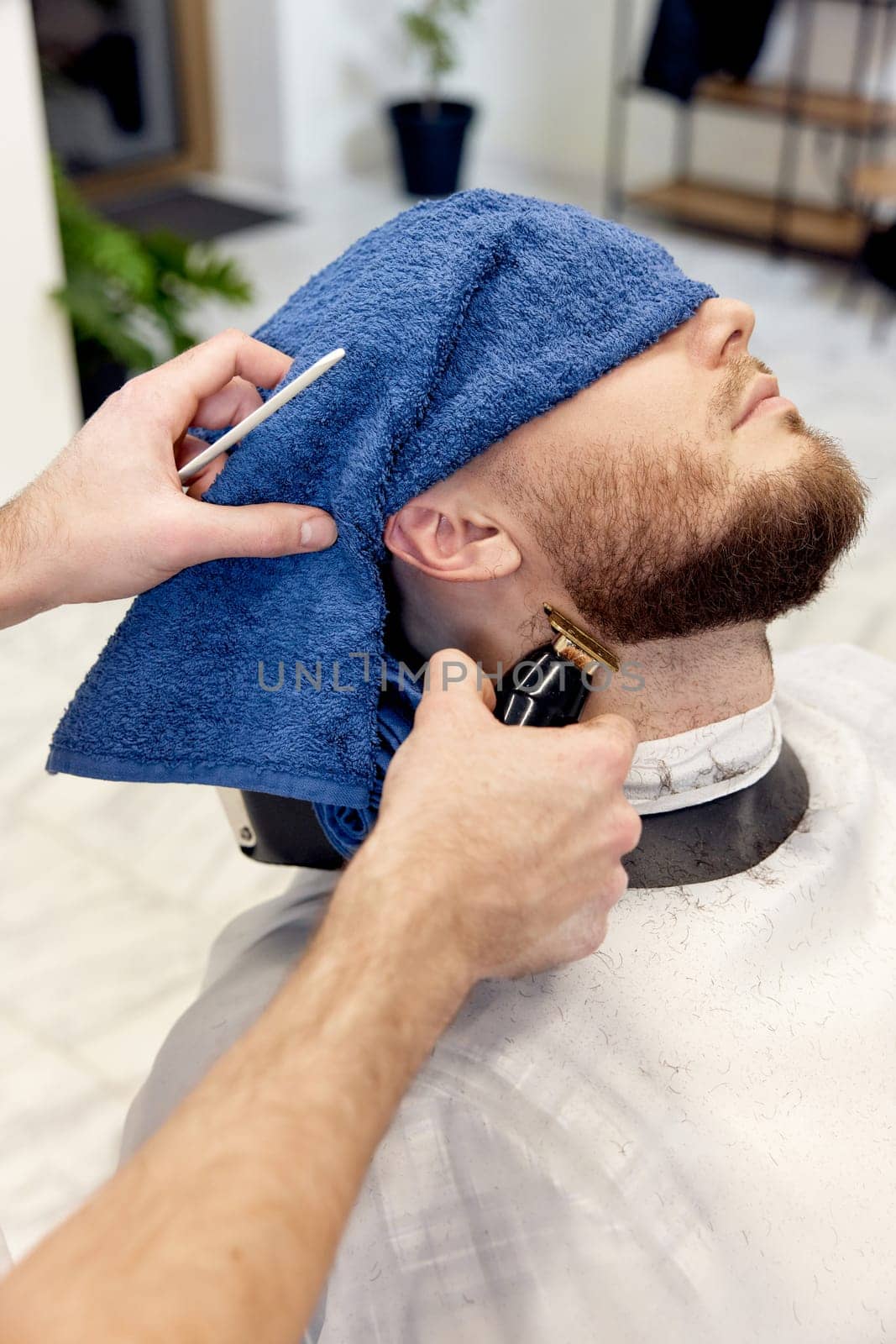 Barber shaving handsome bearded man in barber shop.