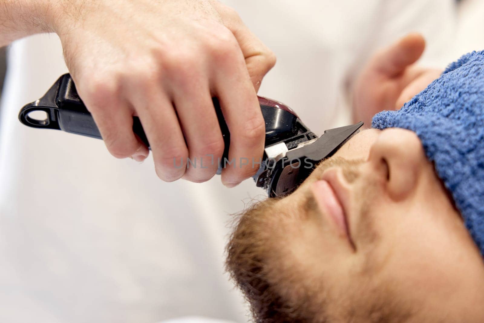 male hands of barber with hair clipper, close up.