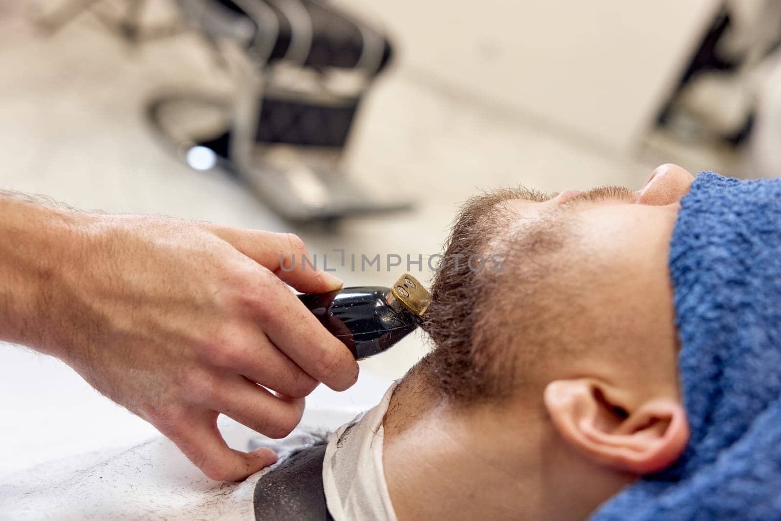 Barber shaving handsome bearded man in barber shop.