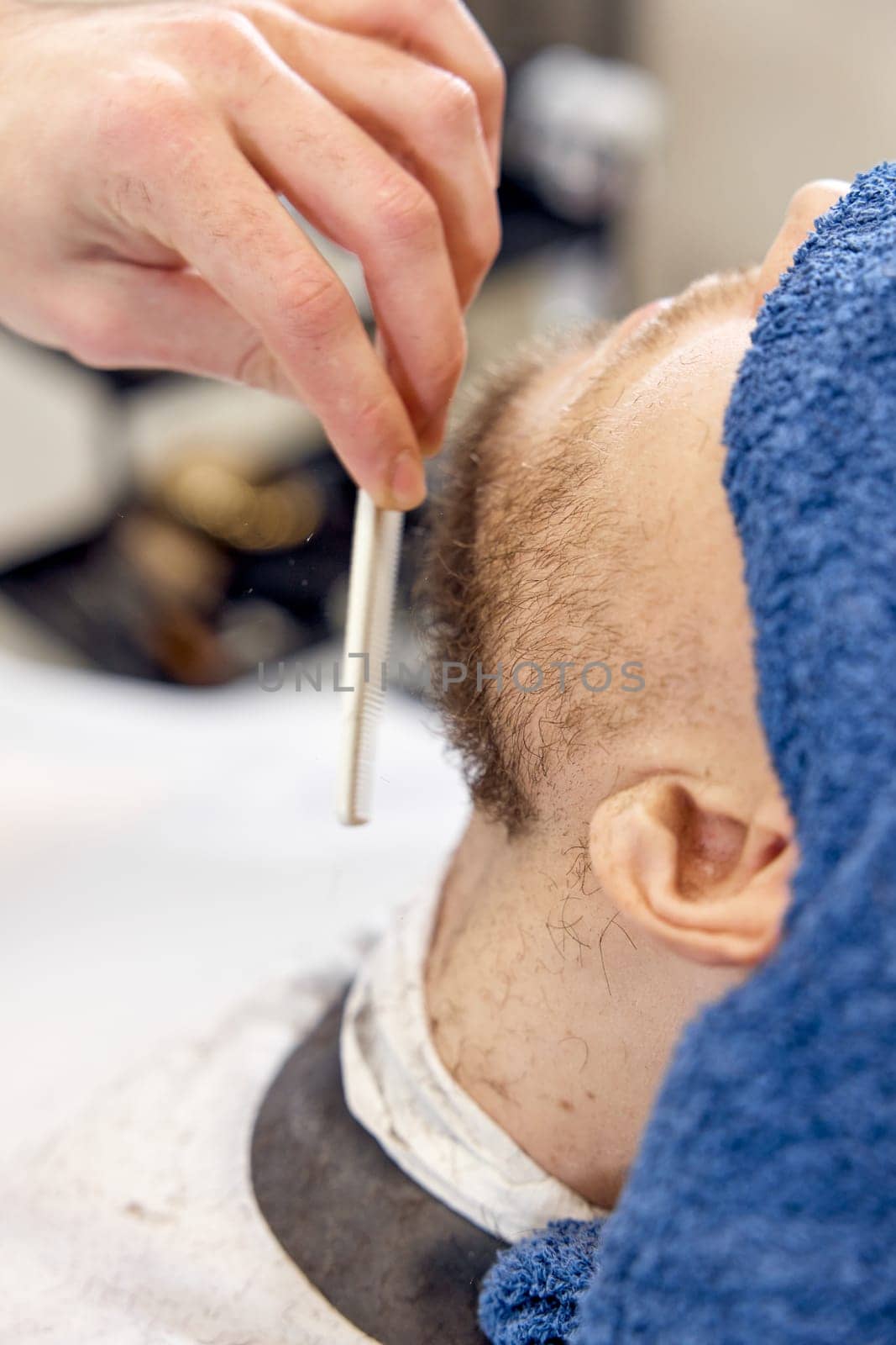 Barber shaving handsome bearded man in barber shop.