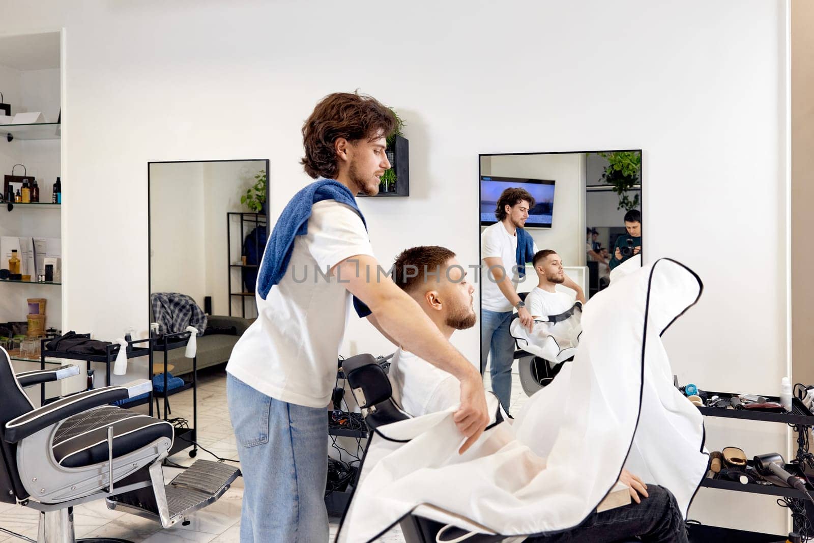 Professional barber during work with man client in barber shop.