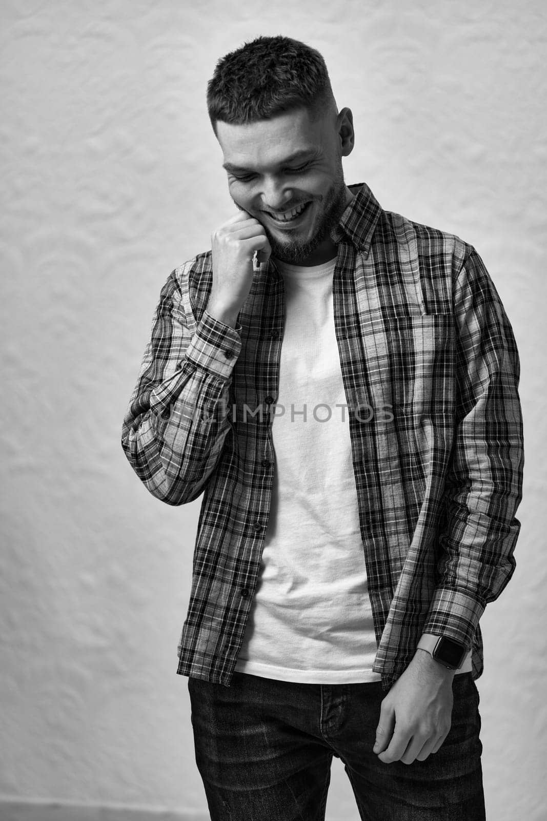 smiling young man with stylish hair and beard in a plaid shirt on gray background. black and white